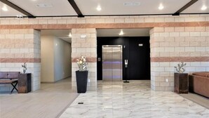 A modern lobby with a marble floor, a black elevator, and a bench. - Scenic View Inn & Suites Moab (Moab)