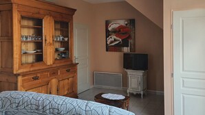 Quarto com um armário de madeira, um quadro, uma televisão e uma porta.
