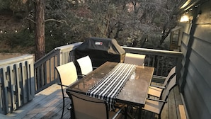 A wooden deck with a table and chairs, a grill, and a railing. - Cozy Family Friendly Lodge, 2 Games Rooms, Hot Tub, EV Charger (Prescott)