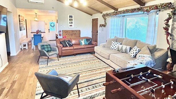 A spacious living area with a high ceiling, wooden beams, a sofa set, a patterned rug, and a foosball table. - Cozy Family Friendly Lodge, 2 Games Rooms, Hot Tub, EV Charger (Prescott)