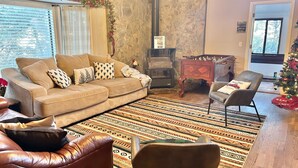 A cozy living room with a sofa, armchair, and a fireplace. - Cozy Family Friendly Lodge, 2 Games Rooms, Hot Tub, EV Charger (Prescott)