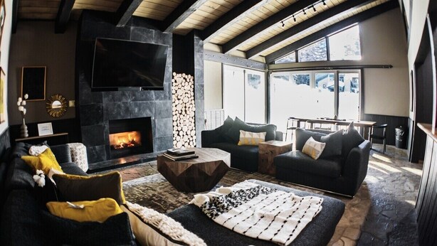 A cozy living room with a fireplace, comfortable seating, and a large window offering a view. - Chamonix 10: Charming, Walk to Canyon Lodge (Mammoth Lakes)