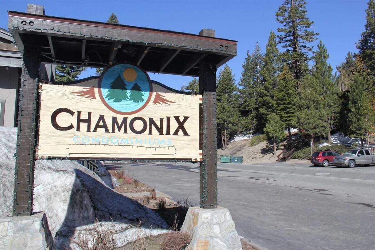 A sign for Chamonix condominiums with a mountain and sun graphic.