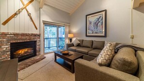 A cozy living room with a fireplace, a sofa, a coffee table, and a painting on the wall. - Chamonix 10: Charming, Walk to Canyon Lodge (Mammoth Lakes)