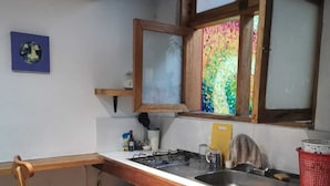 A compact kitchen with a wooden countertop, a gas stove, a sink, and a window with colorful stained glass.