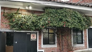 A brick building with a black gate, a 'No Parking' sign, and a potted plant.