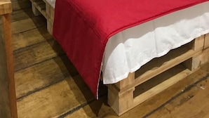 A single-bed room with a wooden headboard, white bedding, and red pillows.