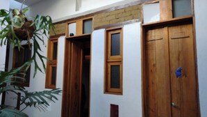 A room with a wooden door, a window with a wooden frame, and a hanging plant.