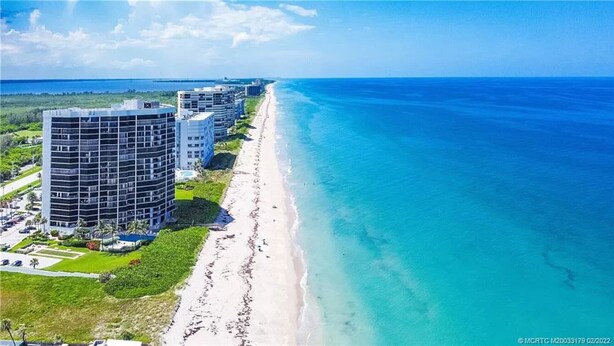 A coastal hotel with a beachfront view, featuring multiple high-rise buildings and a sandy beach.
