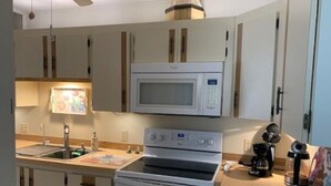 A compact kitchen with a microwave, oven, and coffee maker.