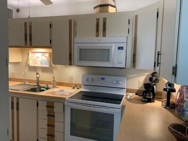 A compact kitchen with a microwave, oven, and coffee maker.