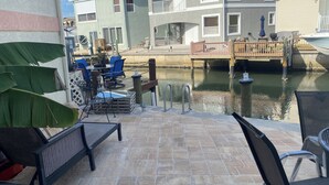 A patio area with outdoor seating, a dock, and a canal view.
