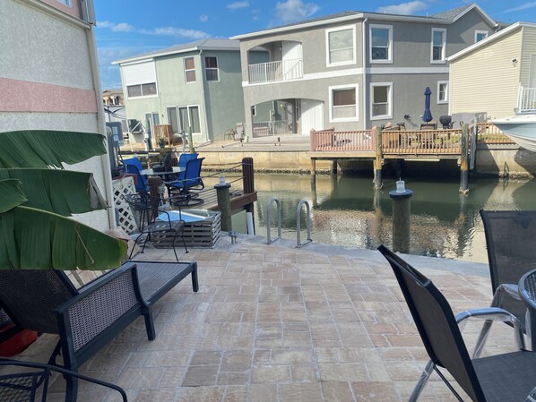 A patio area with outdoor seating, a dock, and a canal view.