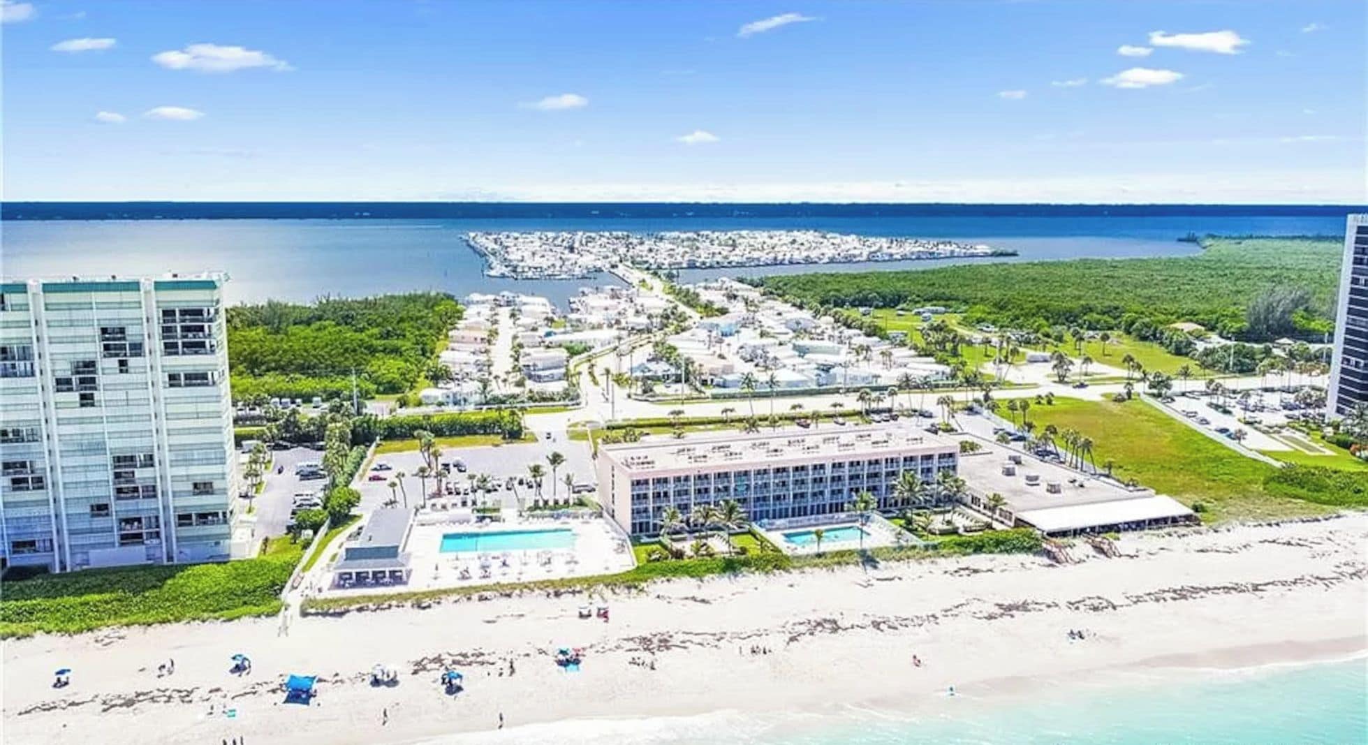 A coastal resort with a beach, a pool, and a marina.