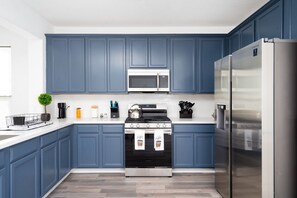 Eine moderne Küche mit blauen Schränken, einem Edelstahl-Kühlschrank, einer Mikrowelle und einem Herd.
