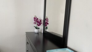 A dark wooden dresser with a small white vase containing purple flowers and a blue tray on top.