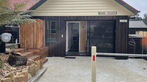 A cabin with a wooden exterior, a green door, and a sign indicating it is a 'Bank House'. - Derby Bank House Cabin- one bedroom with full kitchen. In the centre of town (Derby)
