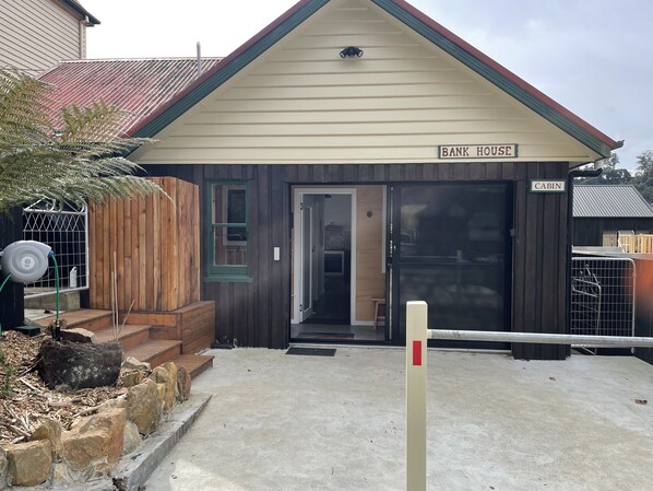 A cabin with a wooden exterior, a green door, and a sign indicating it is a 'Bank House'.