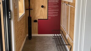 A narrow hallway with wooden walls, a metal rack, and a poster about tin mining. - Derby Bank House Cabin- one bedroom with full kitchen. In the centre of town (Derby)
