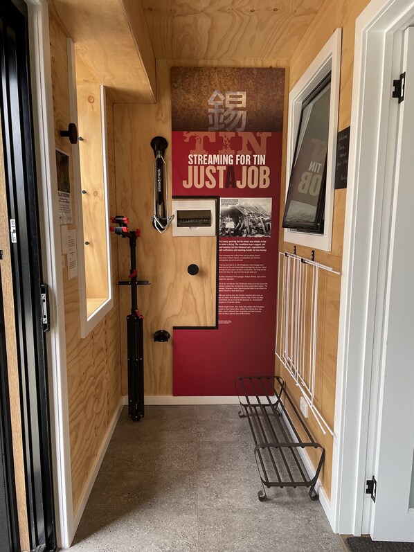 Un couloir aux murs en bois, une étagère en métal et une affiche intitulée « DIFFUSION EN CONTINU POUR UN SIMPLE EMPLOI ».