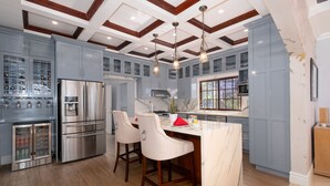A modern kitchen with stainless steel appliances, a marble countertop, and a built-in wine cooler.