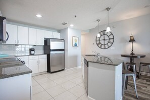 Modern kitchen with a sink, refrigerator, and dishwasher, plus a small island and dining area.