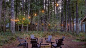 Entorno boscoso con asientos al aire libre y luces colgantes.