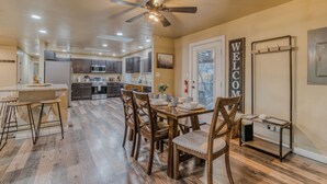 A modern kitchen with a central island, wooden chairs, and a ceiling fan.
