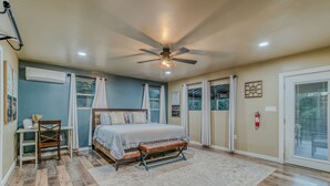 A bedroom with a bed, a bench, a desk, and a ceiling fan.