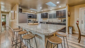 A spacious kitchen with a large island, bar stools, and modern appliances.