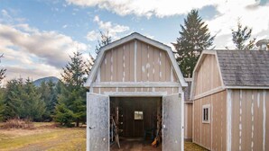 A barn with an open door, revealing a wooden interior with a ladder and a broom. - Little Woods Outpost | Wifi, AC, Hot tub (Randle)
