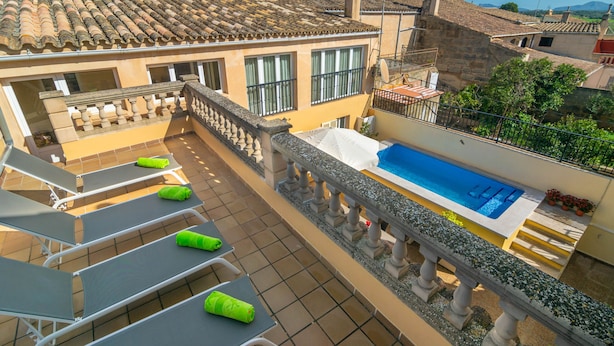 A rooftop terrace with a swimming pool, sun loungers, and a stone balustrade.