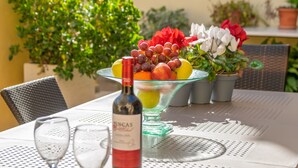 A table with a wine bottle, two glasses, and a fruit bowl.