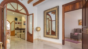 A spacious living area with a polished floor, a large ornate mirror, and a cozy seating area.