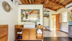 A wooden vanity with a mirror, sink, and storage compartments in a room with a wooden ceiling and a view of a door and hallway. - Escape to your private oasis (Hilo)