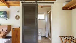 A room with a sliding door leading to a bathroom, a wooden cabinet, and a small table. - Escape to your private oasis (Hilo)