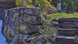 A two-story house with a green exterior and a stone base. - Escape to your private oasis (Hilo)