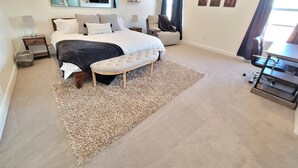 A bedroom with a large bed, a bench, a desk, and a chair. There is a mirror on the wall, a window with curtains, and a rug on the floor. - Pool now open! Pickleball! Game Room! (Washington)