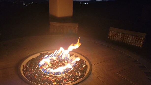 A fire feature with a circular arrangement of glass bottles, surrounded by a wooden deck. - Pool now open! Pickleball! Game Room! (Washington)