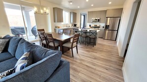 A modern kitchen with stainless steel appliances, a dining area with wooden furniture, and a large window providing natural light. - Pool now open! Pickleball! Game Room! (Washington)