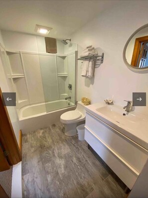 Een bad/douchecombinatie, handdoeken, toiletpapier