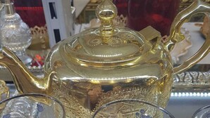 A display of ornate glassware, including a golden teapot and intricately designed glasses. - Apartment near Disney RER A direct (Poissy)