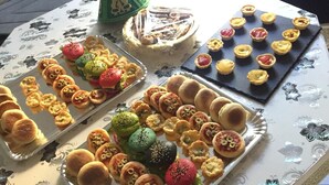 A table with various baked goods, including pastries and tarts, arranged on a patterned tablecloth. - Apartment near Disney RER A direct (Poissy)