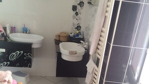A bathroom with a white sink, a black and white tiled floor, a wooden bench, and a towel rack. - Apartment near Disney RER A direct (Poissy)