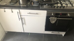 A kitchen with a stove, oven, and white cabinets. - Apartment near Disney RER A direct (Poissy)