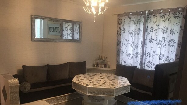A living room with a round coffee table, two sofas, a TV, and a chandelier. - Apartment near Disney RER A direct (Poissy)