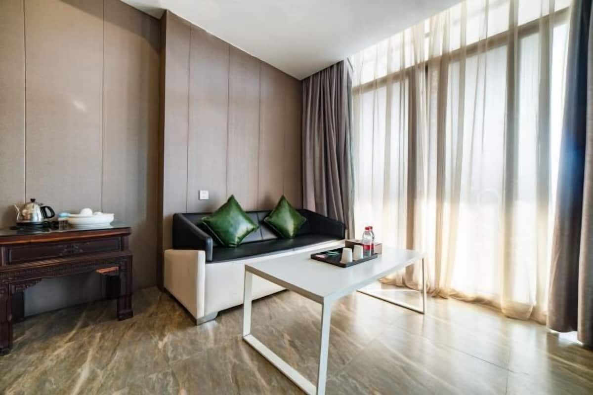 Una sala de estar moderna con un sofá, una mesa de centro, una mesita auxiliar y un ventanal con cortinas.