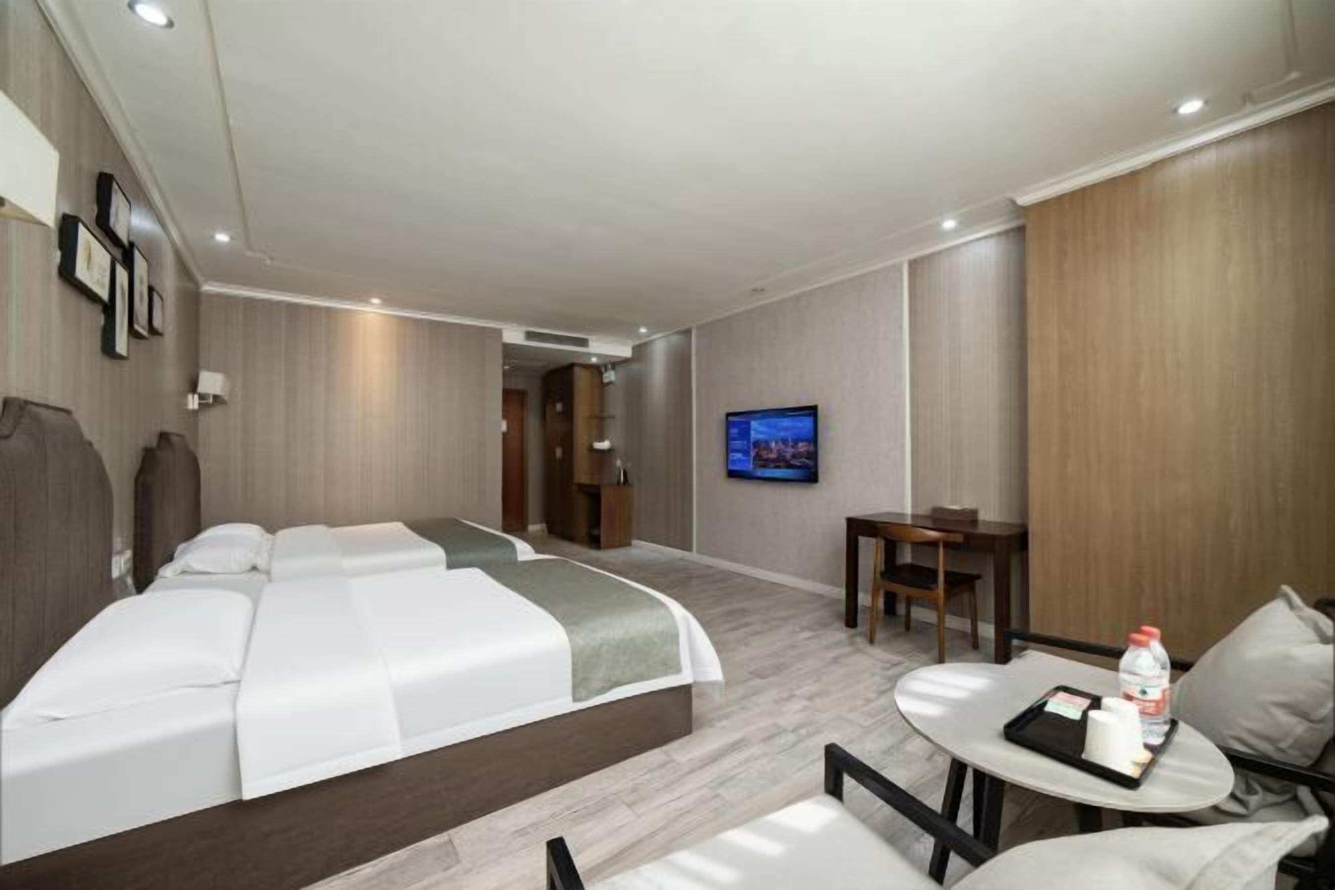 A hotel room with a bed, a TV, a small table with a chair, and a desk.