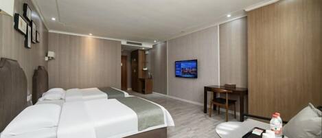 A hotel room with a bed, a TV, a small table with a chair, and a desk.