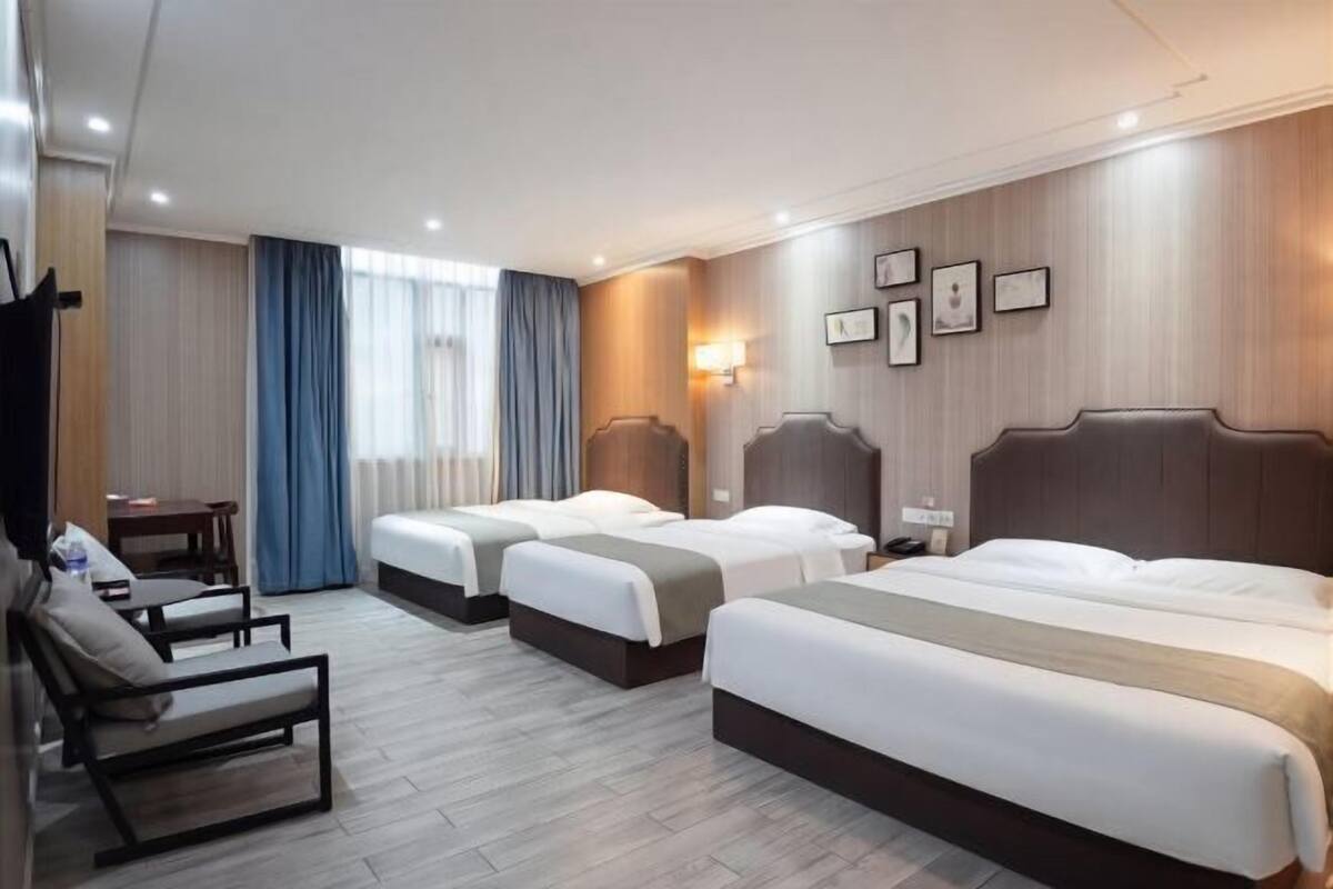 Habitación de hotel con dos camas, un escritorio, una silla y una ventana con cortinas.